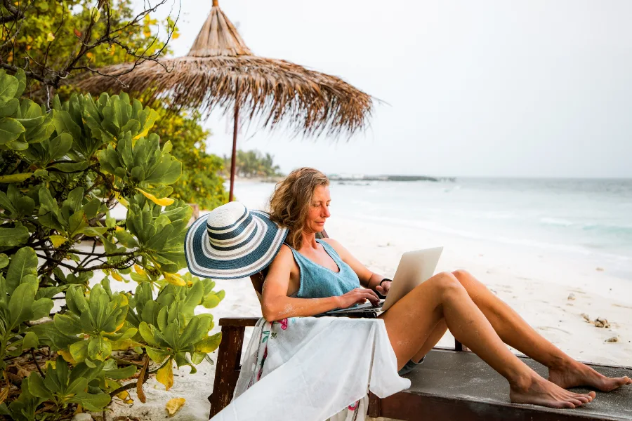 A woman working on a laptop on the beach